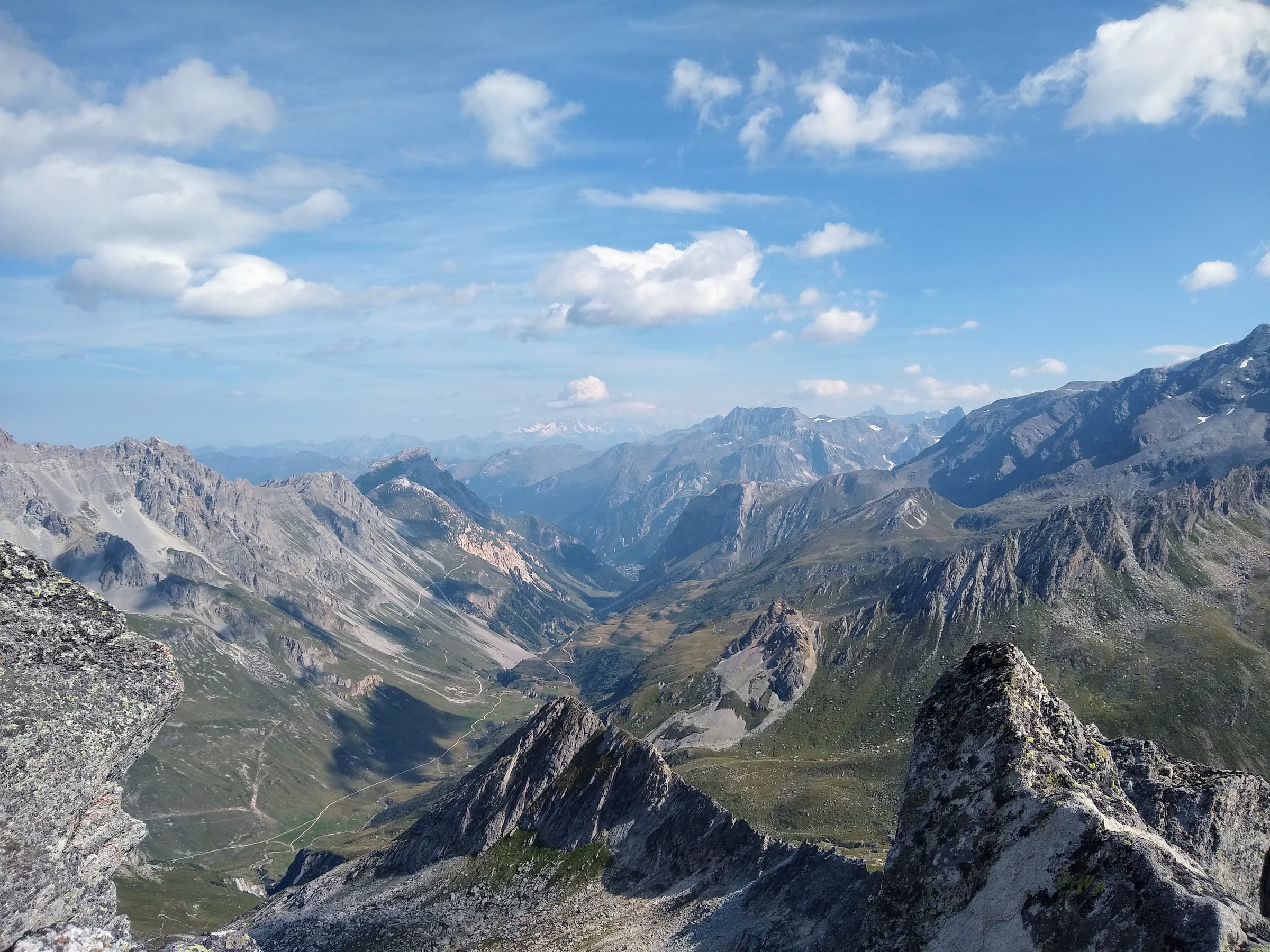 Vallée encaissée entre des sommets et des crêtes rocheuses sous un ciel parsemé de nuages.